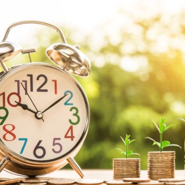 An old-fashioned alarm clock with bells, and three stacks of coins showing growth.